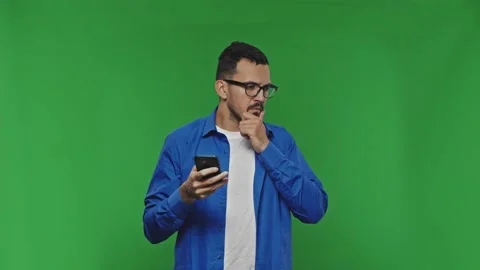 Attractive guy texting on his phone, scratching his beard, thinking, looking at Stock Footage 169865445