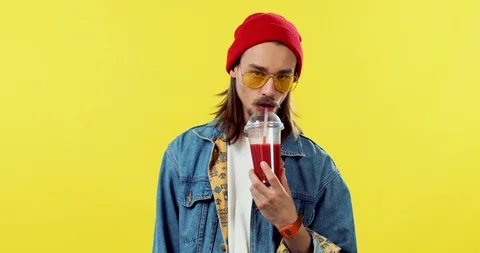 Attractive handsome young guy in the red hat drinking smoothie with a straw Stock Footage 105433898