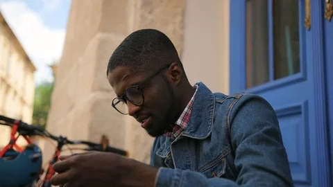 Attractive happy african man in glasses typing in smart phone while relaxing Stock Footage