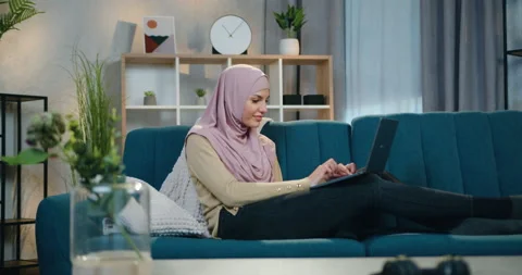 Attractive happy smiling young arabic woman in hijab relaxing on comfortable Stock Footage 150112877