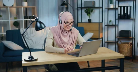 Attractive happy smiling young arabic woman in hijab sitting in front of laptop Stock Footage 150165597