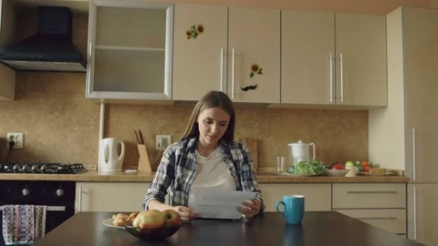 Attractive happy woman recieve good news unfold letter in the kitchen while have Stock Footage