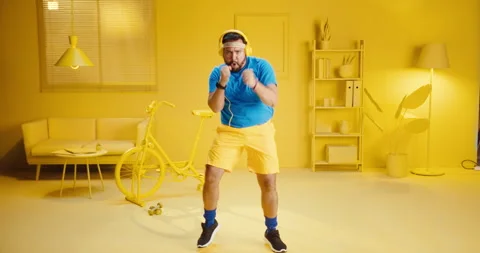 Attractive happy young man doing exercise with punching movement while listening Stock Footage 165865155