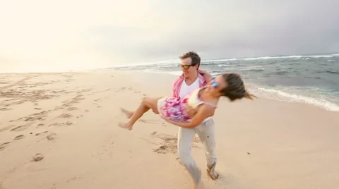 Attractive healthy couple having fun being together running on beach Stock Footage 58166344