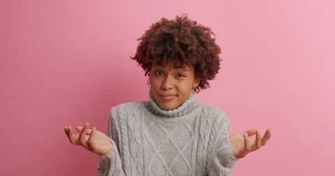 Attractive hesitant dark skinned Afro American woman spreads hands sideways as Stock Footage 142747179