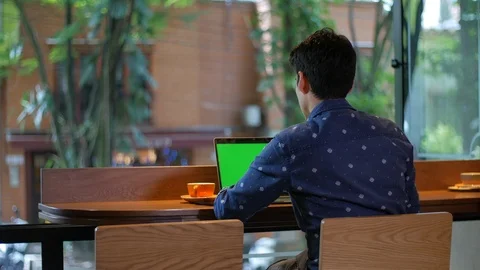 Attractive hispanic man sitting in coffee shop with a laptop drinking coffee Vídeo Stock 101656883