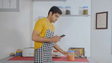 Attractive home chef checking recipe on his smartphone before cooking Stock Footage 144600334