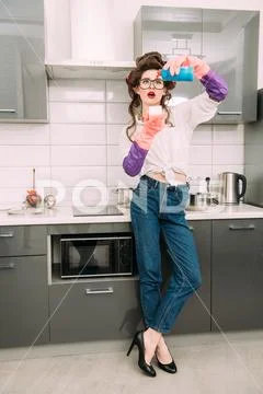 Attractive housewife in casual clothes is cleaning with detergent the counter Stock Photos