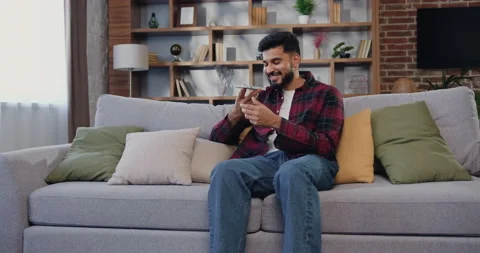 Attractive indian man using smartphone recording answering by audio message in Stock Footage 225538320
