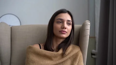 Attractive Indian mixed-race woman looking at camera sit on sofa alone at home Stock Footage 150110053
