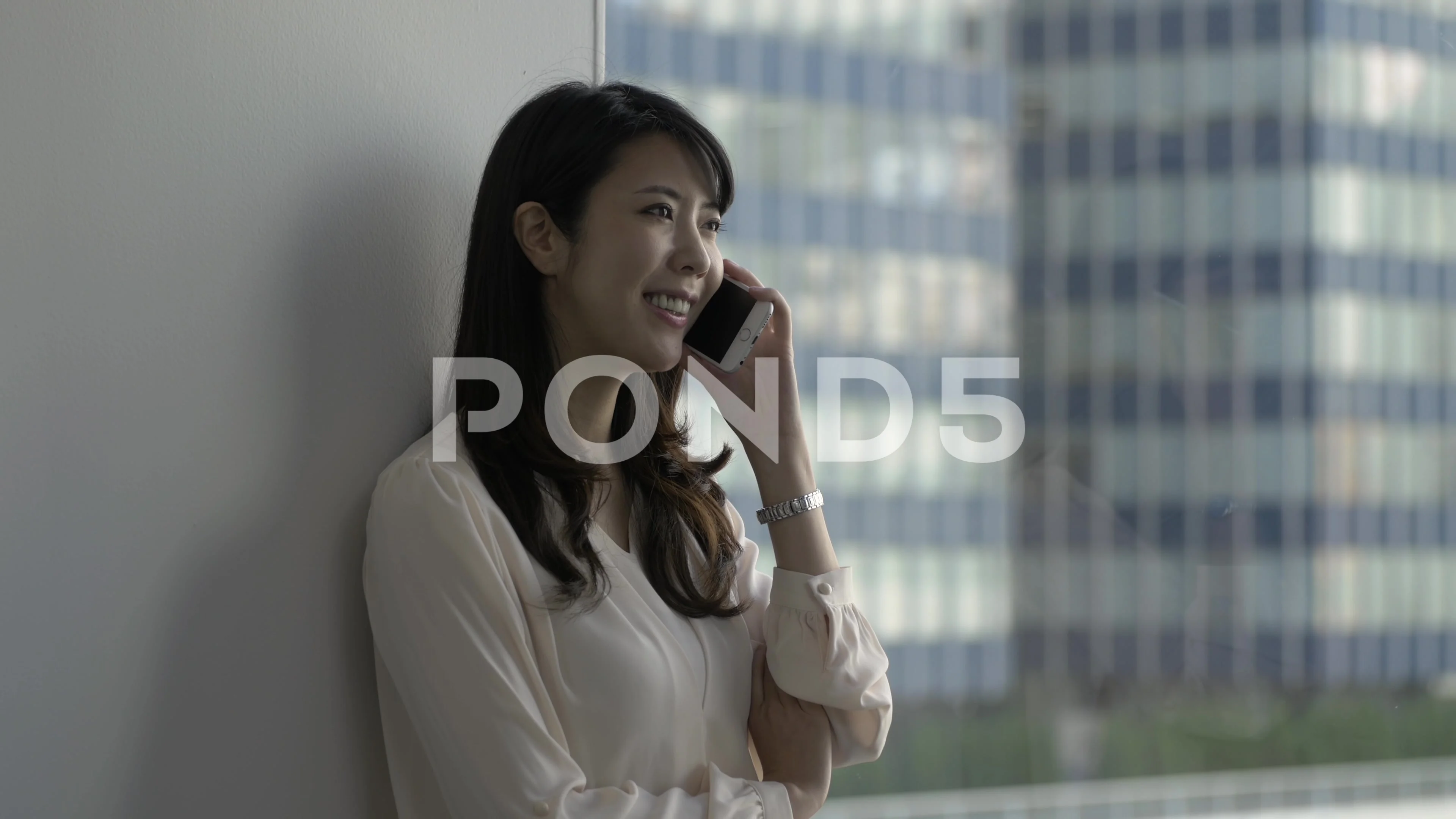 Attractive Japanese young woman talking on the phone in a modern office