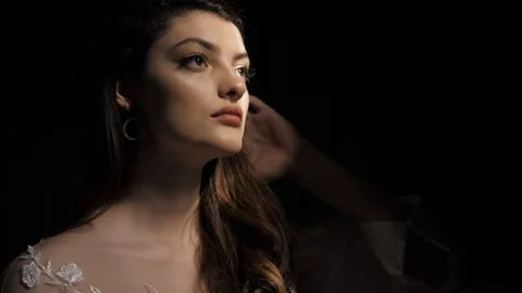 Attractive lady with silver earrings fixes long curly hair Stock Footage 126604859