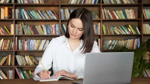 Attractive lady writes in notebook at videocall on laptop Stock Footage 151188387
