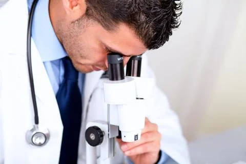 Attractive latin doctor using a microscope Stock Photos