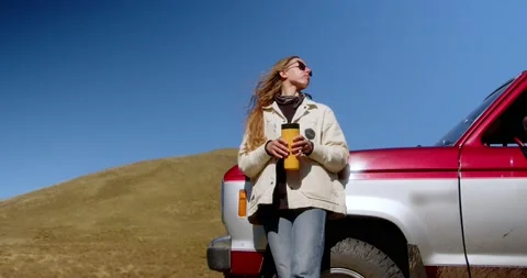 Attractive long-haired girl drinking a drink from a thermos of thermo mugs while Stock Footage 239363710