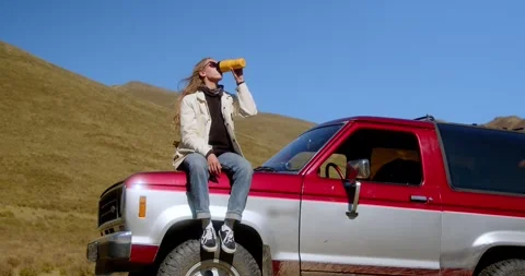 Attractive long-haired girl drinking a drink from a thermos of thermo mugs while Stock Footage 247625890