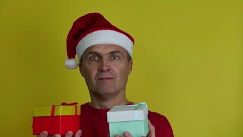 Attractive man 40-50 years old in Santa hat offers gift boxes. Stock Footage 165638255