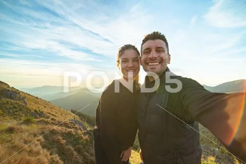 The attractive man and a woman taking a selfie on the mountain background Stock Photos