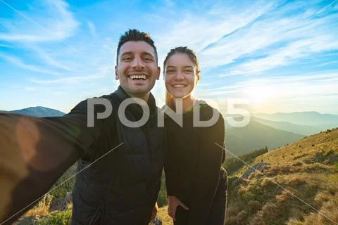 The attractive man and a woman taking a selfie on the mountain background Stock Photos