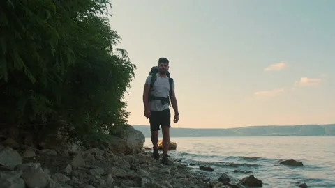 The attractive man with backpack walking along the shore. slow motion Stock Footage 159732712