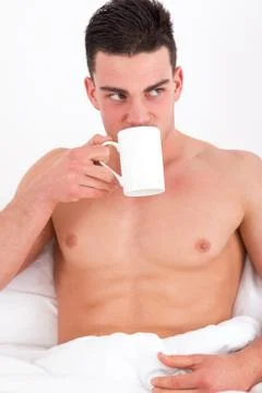 Attractive man in bed drinking coffee Stock Photos