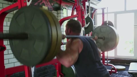 An attractive man bodybuilder does squats with barbell at gym Stock-Footage 143521401