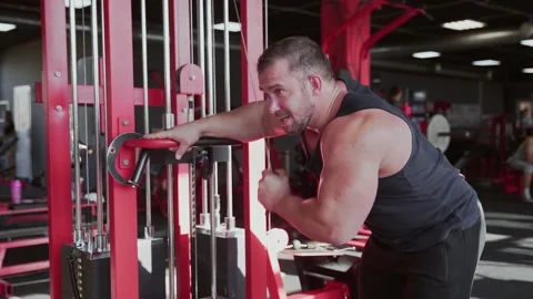 An attractive man bodybuilder Doing Exercises For The Muscles Of The Arms on Stock Footage 143521494