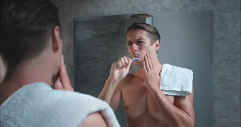 Attractive man brushes teeth in bathroom in morning. While brushing feels sharp Stock Footage 271175185