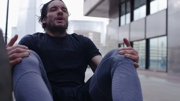 Attractive man doing abdominal crunches outdoors in the city, in slow motion Stock Footage 85576857