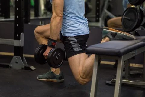 Attractive man doing lunges step-ups with heavy dumbbell. Stock Photos