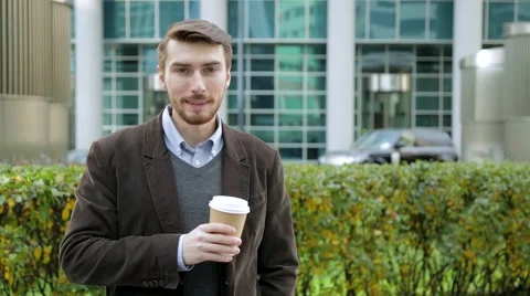 Attractive man drinking coffee or tea from paper cup, looking at camera, smiling Stock Footage 68402103