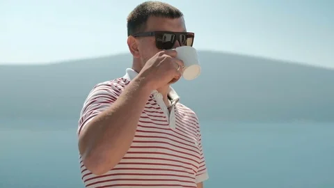 Attractive man drinks coffee and looks to distance outdoors Stock Footage 76101071