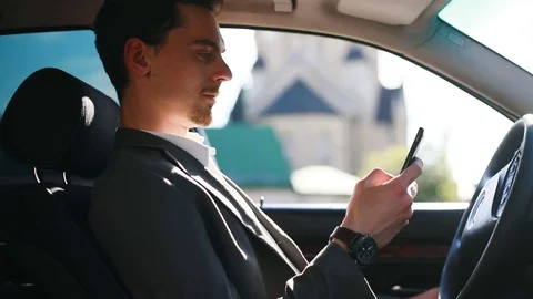 Attractive man driver sitting car side view face using mobile phone touchscreen Stock Footage