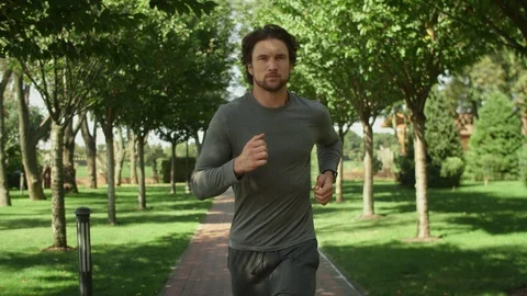 Attractive man, guy jogging in the park on a background of trees, fitness watch Video stock 115406869