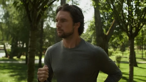 Attractive Man, guy jogging in the park on a background of trees, Close-up Stock-Footage 115407419