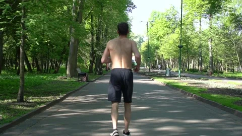 Attractive man, guy jogging in the park on a background of trees. Stock Footage 130819388
