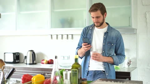 Attractive man at home using smartphone in kitchen sending message Stock Footage 159537663