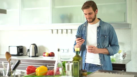 Attractive man at home using smartphone in kitchen sending message Stock Footage 159538012