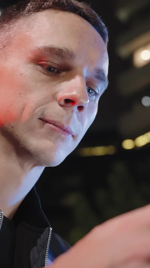 An attractive man in a jacket is using his cell phone outside at nighttime Stock Footage 275245848