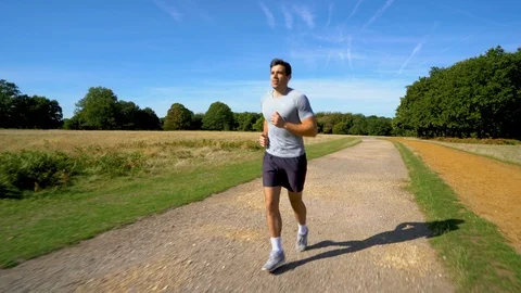 Attractive man jogging along path towards camera 4K Stock Footage 96046351