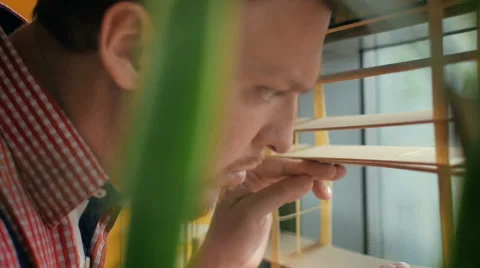 Attractive man looking through the blinds of the window to the street Stock Footage 49336238