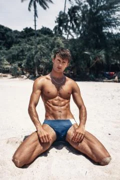 Attractive man of model appearance posing on tropical beach Foto stock