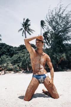 Attractive man of model appearance posing on tropical beach Stock Photos