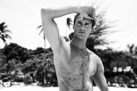 Attractive man of model appearance posing on tropical beach Stock Photos