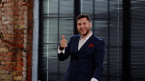 Attractive man in a nice suit laughs, has fun and shows thumbs up. Businessman Stock Photos