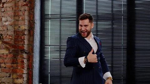 Attractive man in a nice suit laughs, has fun and shows thumbs up. Businessman Stock Photos
