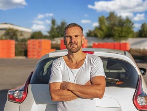 Attractive man posing against the background of a white car. Stock Photos