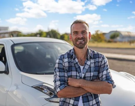Attractive man posing against the background of a white car. Stock Photos