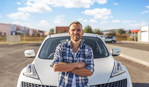 Attractive man posing against the background of a white car. Stock Photos