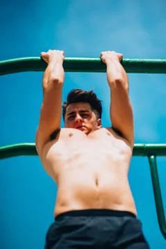 Attractive man pull-ups on a bar against blue sky Stock-Fotos